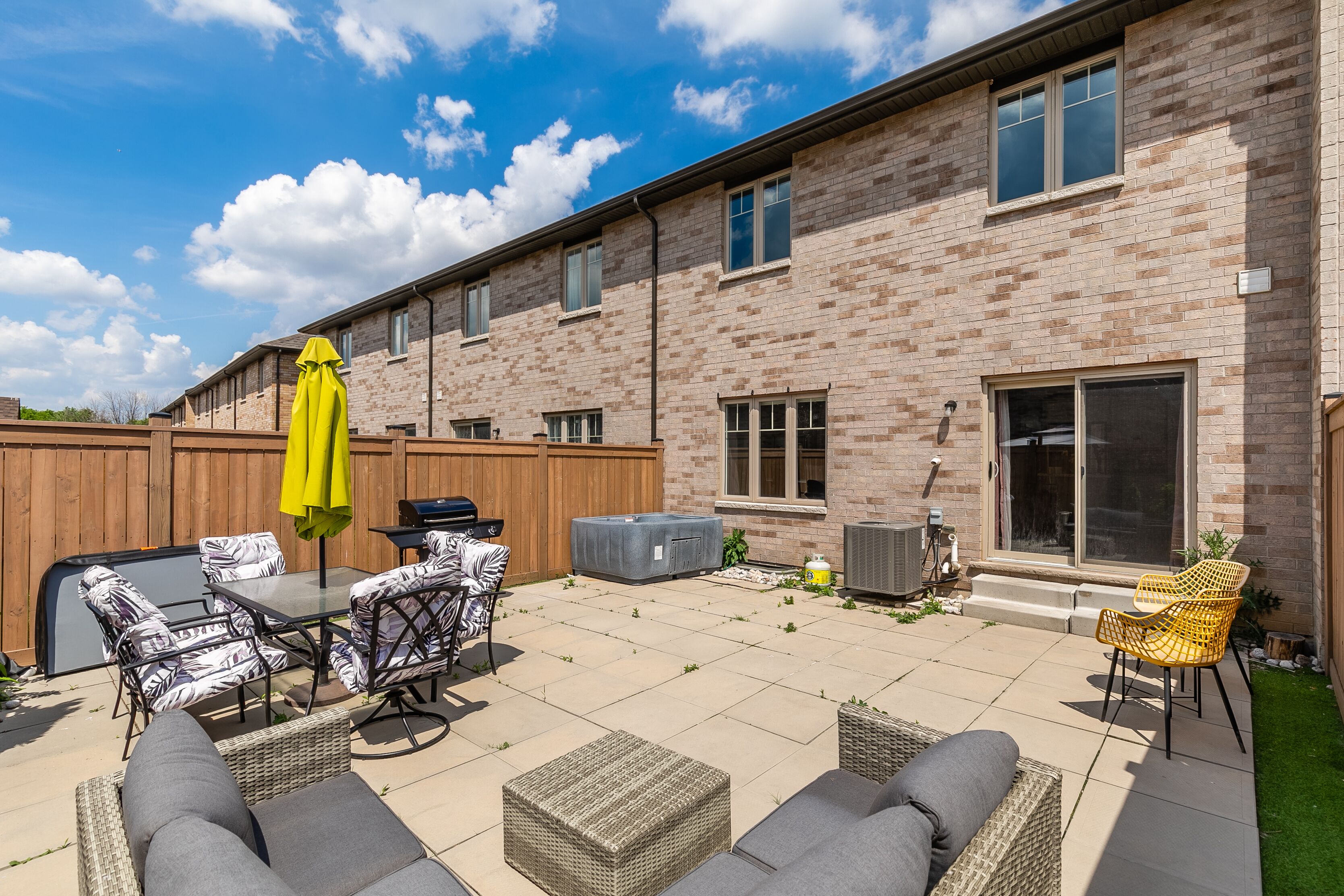 Une terrasse avec mobilier d’extérieur, un barbecue et un espace salon abrité.