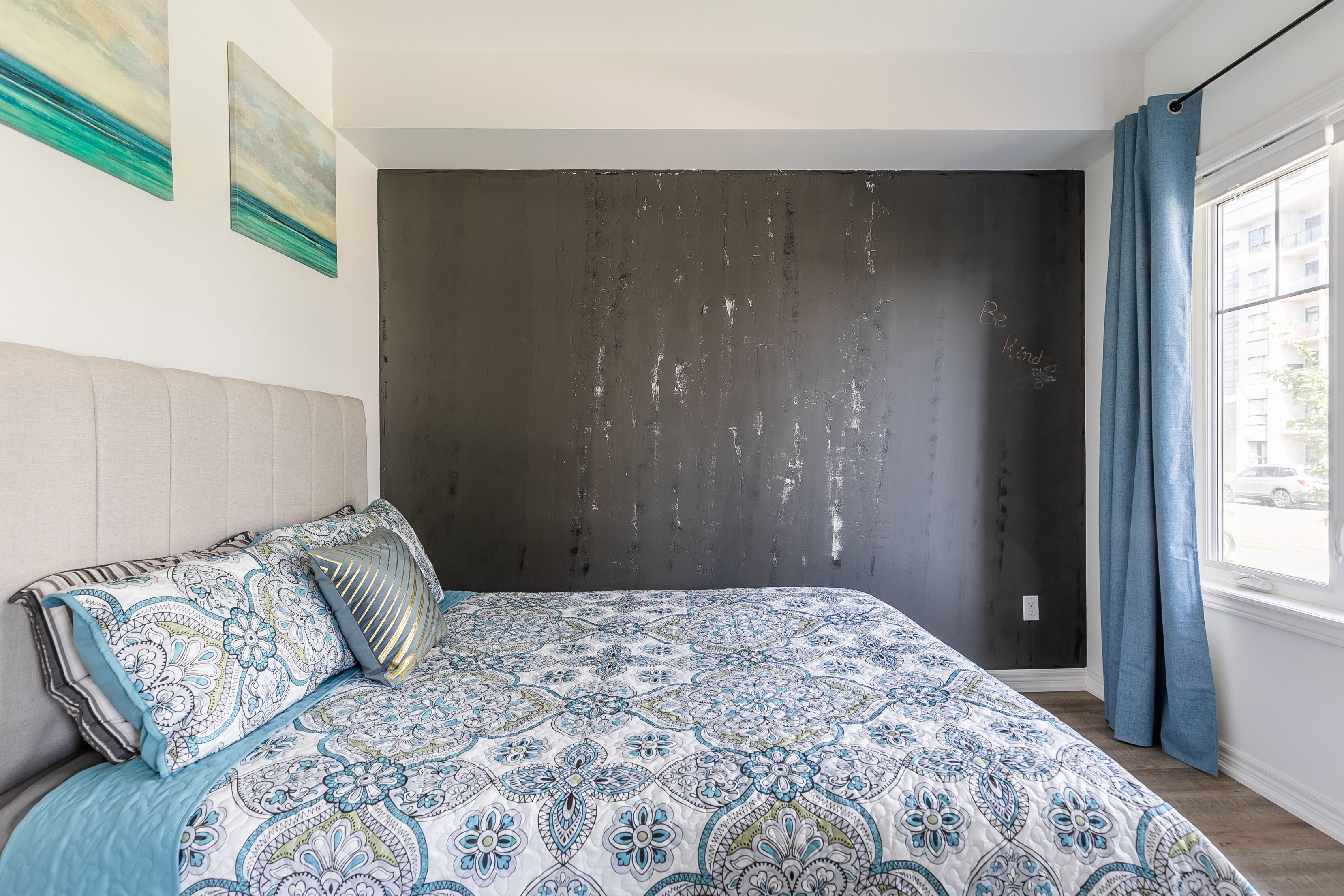 Un dormitorio con una cama grande, una pared oscura y una ventana con cortinas.