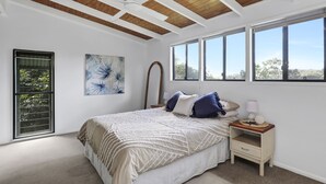 Una camera da letto con un letto grande, un comodino, una ventola a soffitto e una finestra vista alberi.