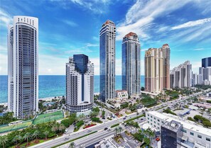 Zona urbana com arranha-céus, céu azul límpido e vista para o oceano.