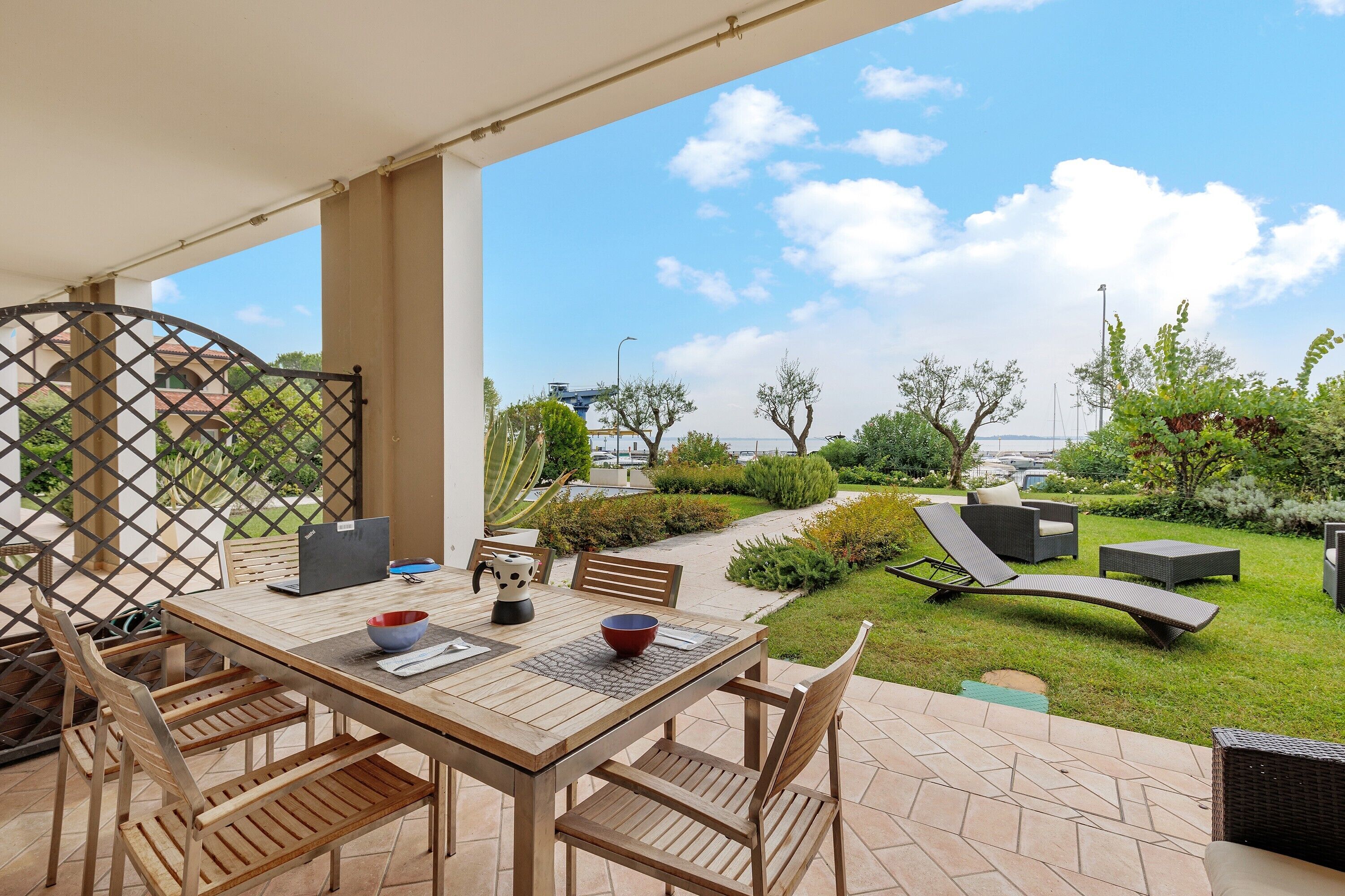 A patio with a table and chairs, a laptop, and a bowl.
