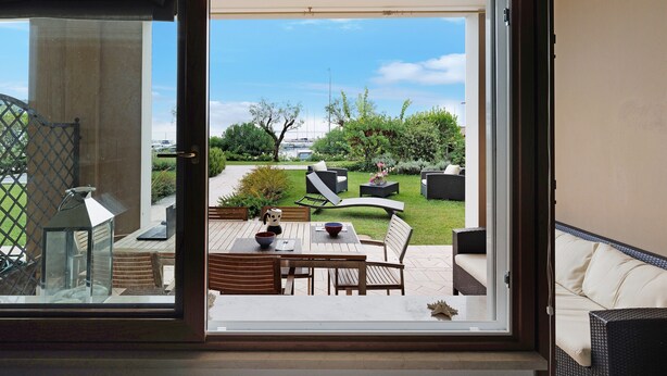 Vista a través de un ventanal hacia un patio exterior con una mesa, sillas y un sofá.