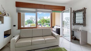 Una sala de estar moderna con un sofá, un ventanal corredero al exterior y una pequeña consola.