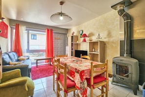 A dining area with a table, chairs, and a wood-burning stove. - Villa 'Le Koala' with Mountain View, Private Terrace and Private Garden (Villard-de-Lans)