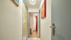 Un pasillo con una puerta, un radiador y una lámpara en el techo.