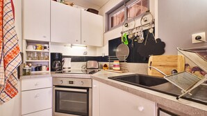 Una cocina con gabinetes blancos, un horno de acero inoxidable, un lavamanos y un ventanal con vistas.