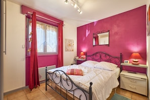 A bedroom with a bed, bedside tables, a window with curtains, a radiator, and a wall-mounted mirror. - Villa 'Le Koala' with Mountain View, Private Terrace and Private Garden (Villard-de-Lans)