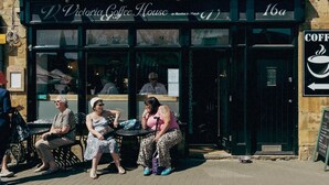 An outdoor seating area in front of Victoria Coffee House, with three people seated at tables. - Elegant & stylish home in historic town centre - Pass the Keys (Moreton-in-Marsh)