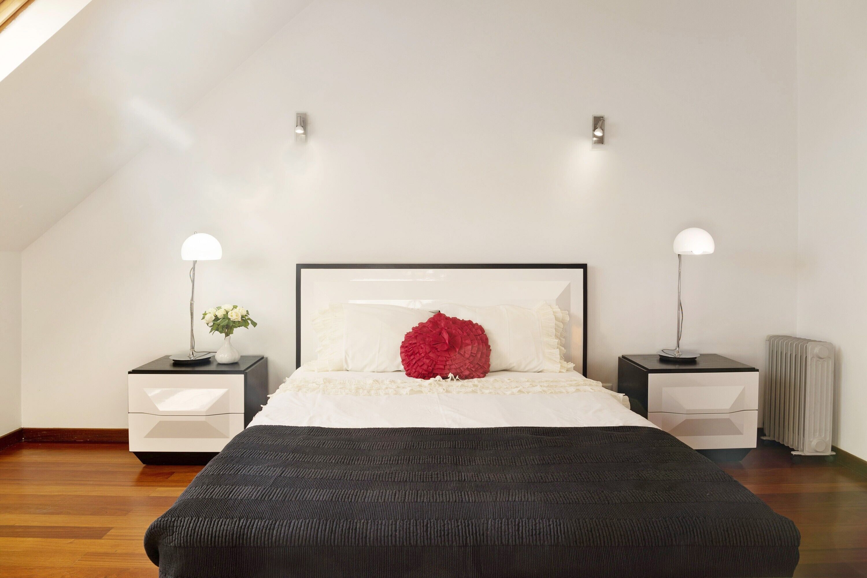 Une chambre à coucher avec un lit, deux tables de chevet, un radiateur et un luminaire au plafond.