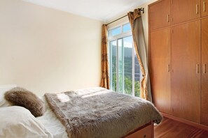 Une chambre à coucher avec un lit, une armoire et une fenêtre avec des rideaux.