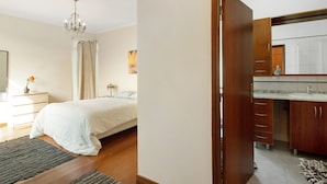 Ein Schlafzimmer mit Bett, Nachttisch, Lampe und Blick ins Bad.