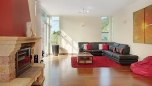 Ein Wohnzimmer mit Kamin, einem schwarzen Ecksofa und einem roten Teppich.