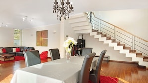 Ein modernes Wohnzimmer mit Essbereich, einer Treppe und einer Chandelier.