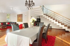 Un salon moderne comprenant un coin repas, un escalier et un lustre.