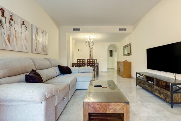 A living room with a sofa, coffee table, TV, and artwork on the wall.
