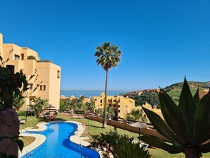A resort with a swimming pool, palm trees, and a view of the sea.