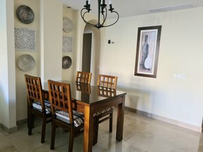 Un coin repas avec une table et des chaises en bois, des œuvres d’art décoratives au mur et un lustre.