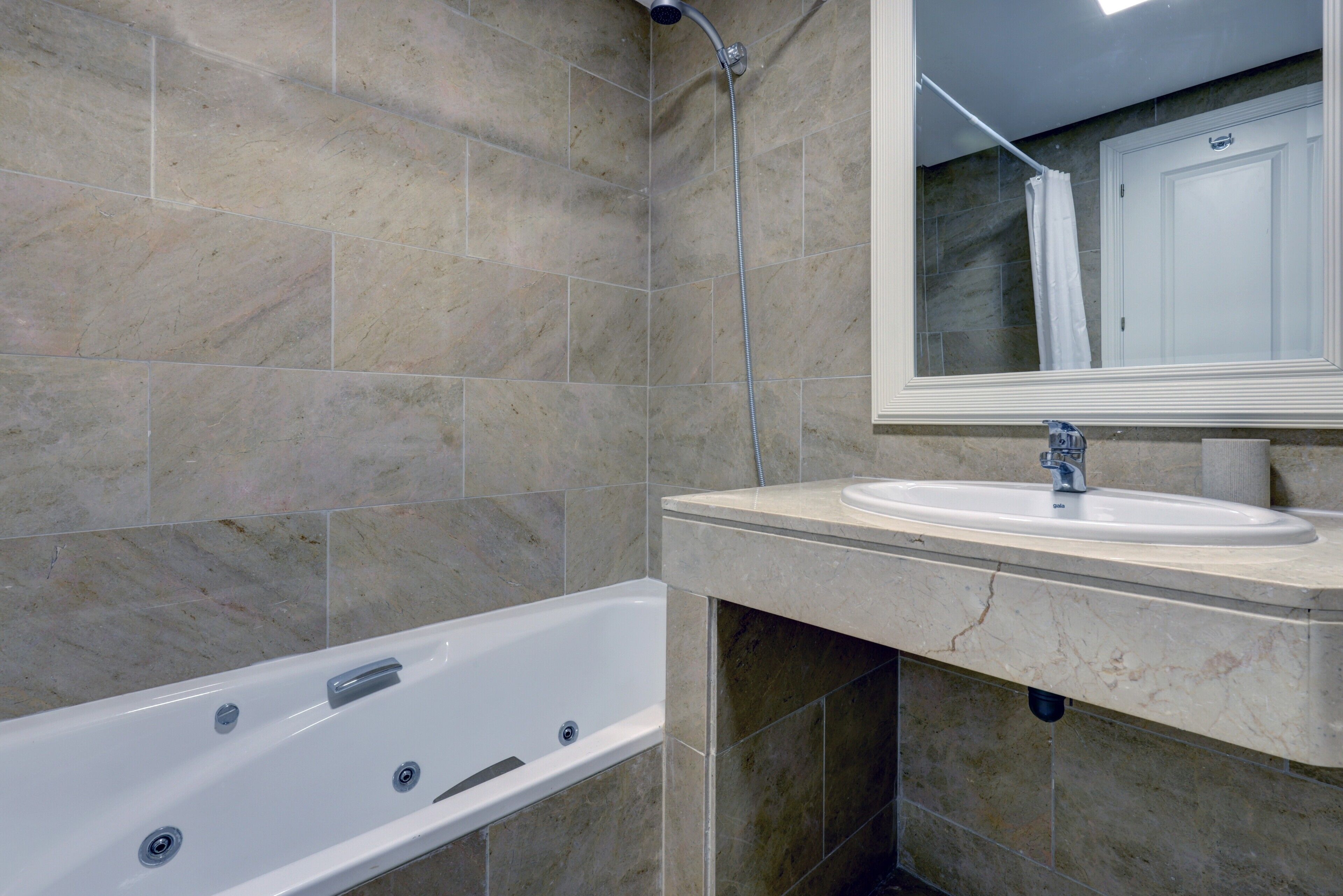 A bathroom with a bathtub, a sink, and a mirror.