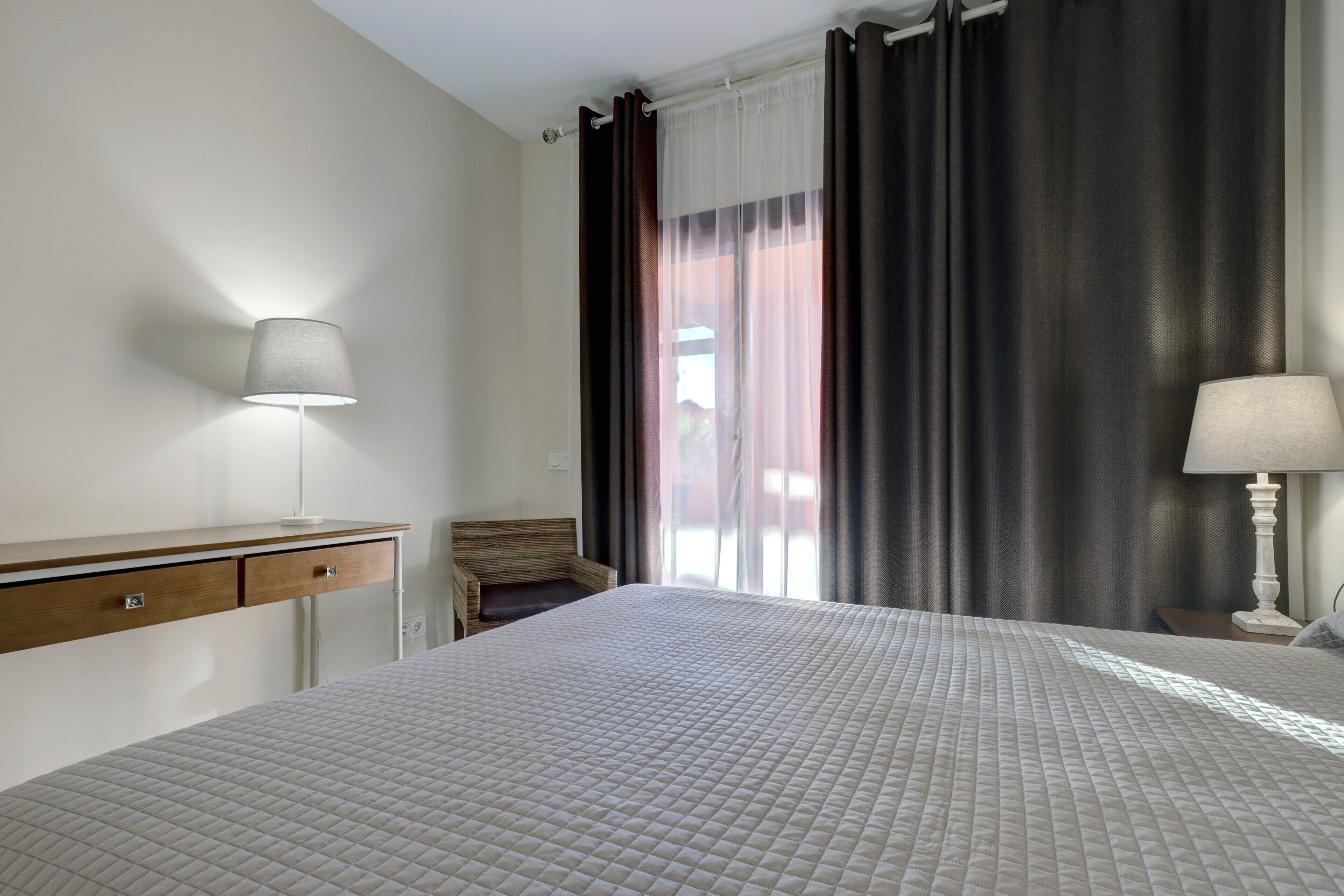 Een hotelkamer met een bed, nachtkastjes, een bureau en een stoel.