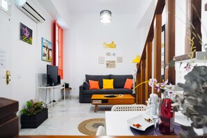 A living room with a sofa, a coffee table, a TV, and a wall with motivational words.