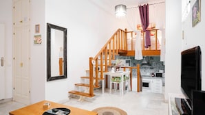 Een moderne woonkamer met een houten trap, een eethoek en een keuken.