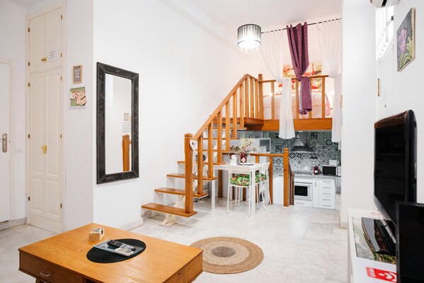 A modern living room with a wooden staircase, a dining area, and a kitchen.