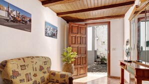A living room with a patterned sofa, a wooden door, a potted plant, and a console table. - Holiday Home "Casa Los Diablitos" – Family-Friendly with Mountain Views, Terrace & Wi-Fi (Santa Cruz de Tenerife)
