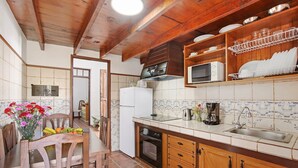 A kitchen with wooden cabinets, a microwave, a sink, and a dining area with chairs and a table. - Holiday Home "Casa Los Diablitos" – Family-Friendly with Mountain Views, Terrace & Wi-Fi (Santa Cruz de Tenerife)