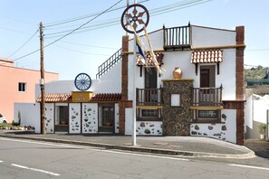 Un edificio con fachada de piedra, un balcón y un asta de banderas.