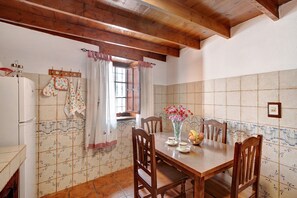 Un coin repas avec une table en bois, des chaises, un vase de fleurs et un mur recouvert de carreaux.