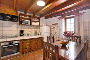 Une cuisine avec des meubles de rangement en bois, un four à micro-ondes, un réfrigérateur et une table à manger avec des chaises.