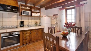 A kitchen with wooden cabinets, a microwave, a refrigerator, and a dining table with chairs. - Los diablitos 2B Holiday Home – Family-Friendly, Mountain Views, Balcony & Wi-Fi (Santa Cruz de Tenerife)