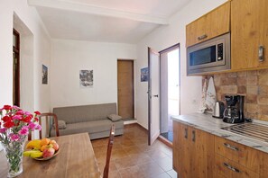 Une cuisine équipée d’un four à micro-ondes, d’une machine à café et d’un coin repas avec une table et des chaises.