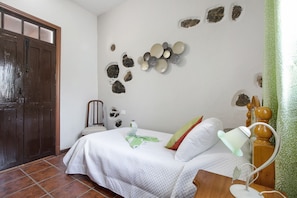 Une chambre à coucher avec un lit, une table de chevet, une lampe et des éléments décoratifs sur les murs.