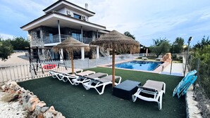 Zona de piscina con sillas de descanso, una piscina y un edificio con balcón.