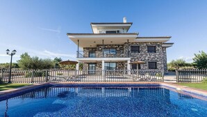 Una casa de piedra de dos pisos con una piscina delantera.