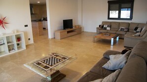 Ein modernes Wohnzimmer mit Sofa, Couchtisch, Fernseher und Schachbrett.