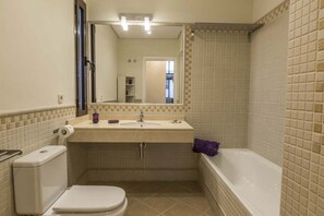 Un baño con inodoro, lavamanos, espejo y bañera.