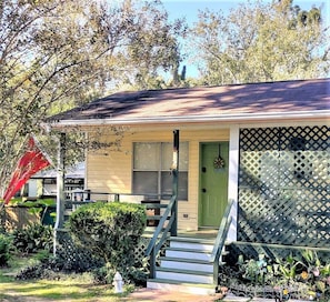 Guests can enter this charming home through the front door, flanked by lush greenery and a decorative wreath.