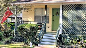 A single-story house with a front porch, a green door, and a lattice screen. - COZY- Quiet Cottage Pets Kitchen (Tallahassee)