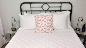 A bed with a white quilted mattress, a metal headboard, and two bedside tables with lamps. - COZY- Quiet Cottage Pets Kitchen (Tallahassee)