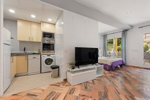 Un appartement moderne doté d’une cuisine, d’une télévision, d’un lit et d’un balcon.