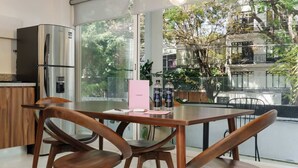 A modern kitchen with a dining area, large windows, and a view of trees and a building. - w* | Splendid 1BR with Perfect Balcony in Polanco (Ciudad de México)