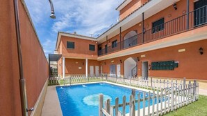 A swimming pool with a wooden fence, a covered area, and a building with balconies. - Holiday Apartment 'Torero II' with Pool, Private Balcony and Wi-Fi (Sevilla)