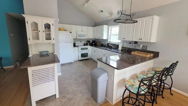 A kitchen with white cabinets, a granite countertop, a built-in oven, and a hanging light fixture. - OBX~Beach~Sunsets~Bike Path~Mini Golf~Seafood~Shops~All within 1/2 mile away (Kill Devil Hills)