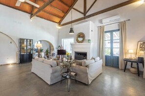 Amplia sala de estar con chimenea, un conjunto de sofás, una mesa de centro y un televisor.