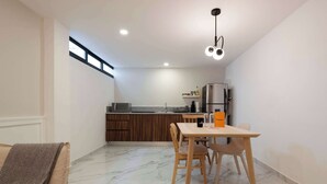 Une cuisine moderne avec un coin repas, des meubles en bois et un réfrigérateur encastré.