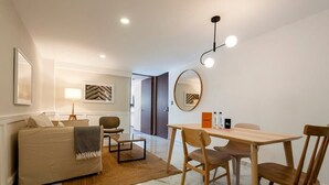 Un salon moderne avec un canapé, une table à manger et des chaises, une lampe et un miroir.