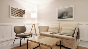 Un salon comprenant un canapé, un fauteuil, une table basse et deux œuvres d’art encadrées accrochées aux murs.