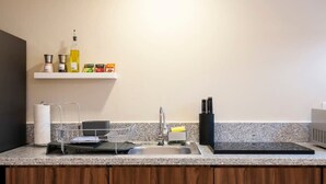 Une cuisine dotée d’un plan de travail en granit, d’un évier en acier inoxydable et d’un meuble en bois en dessous.